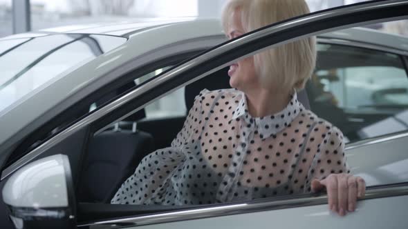 Positive Caucasian Senior Woman Opening Door and Sitting on Driver's Seat