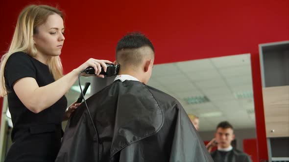 Young Hair Stylist Shaves the Back of the Head of the Client's Salon Spa Center