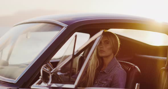 Beautiful woman in a vintage car at sunset