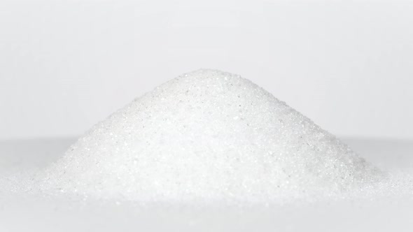 Pile of white sugar rotating on white background