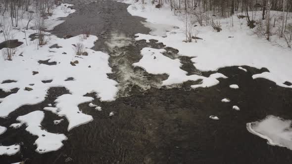 Aerial flying over river during Winter snowfall