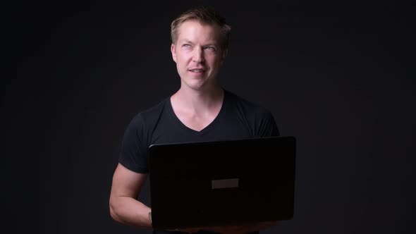 Young Handsome Man with Laptop Against Black Background