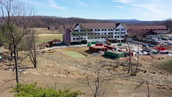 Aerial push in over the trees revealing Cacapon State Park lodge expansion construction in the mount