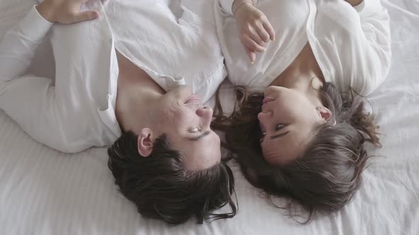 Overhead Shot Happy Young Couple Lying on the Bed Talking Close-up. Top View Relaxing Man and Woman