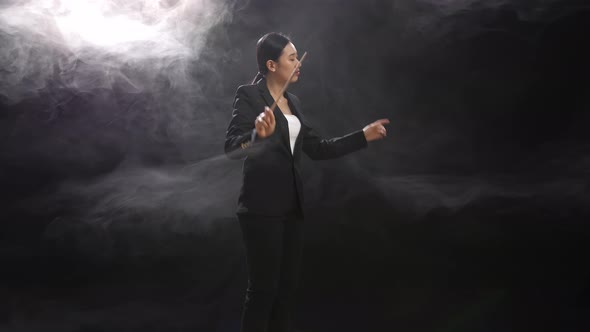 Side View Of Asian Conductor Woman Holding A Baton And Showing Gesture Quickly In The Black Studio