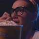 Woman with glasses watching a scary horror movie at the cinema and eating popcorn - VideoHive Item for Sale