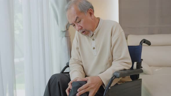 Asian Senior Elderly disabled man sit on wheelchair, suffering from injured leg at nursing home.