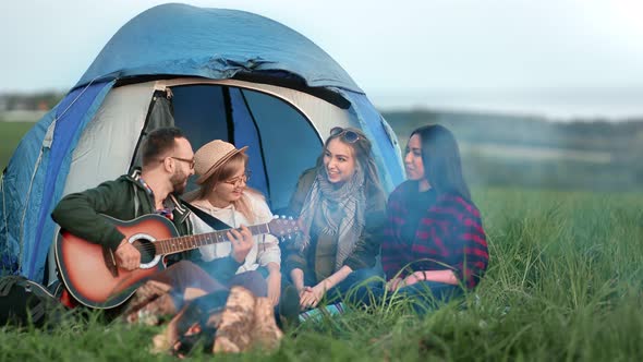 Group of Friends Enjoying Halt Near Bonfire Playing Guitar and Singing Song