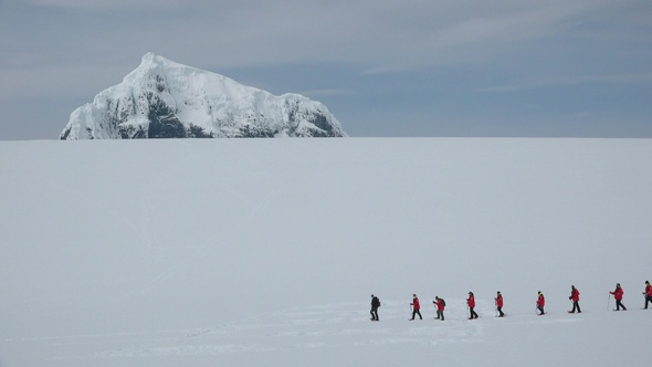 Antarctica Peninsula.  People hikers climbing mountain, team work, travelling, trekking.