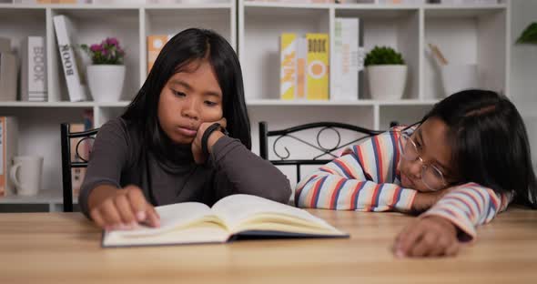 Two bored girls reading a book