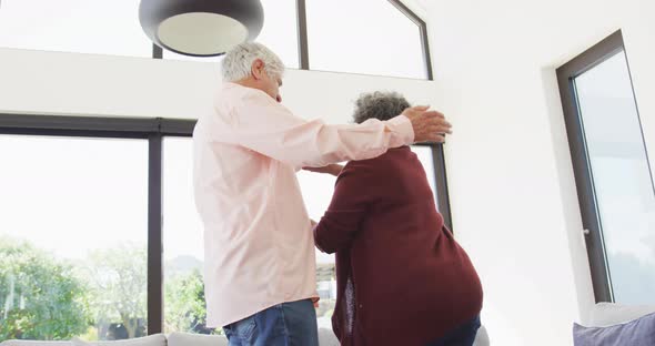 Happy senior diverse couple dancing in living room at retirement home