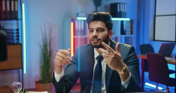 Office Coach in Suit Holding Business Training on Camera from Nightly Lighted Office Room