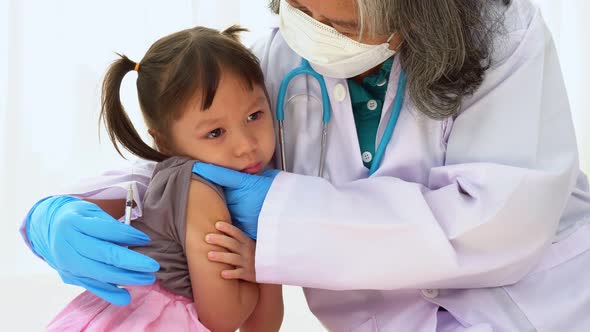 Doctor holding syringe for prepare vaccinated in the shoulder of Asian girl kids in the hospital. Pe