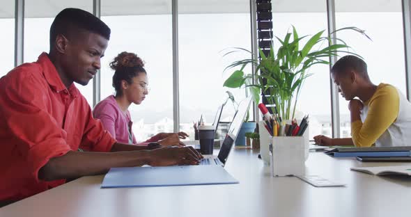 African american creative businessman celebrating in office, with diverse female colleagues working