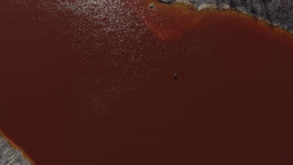 Sun reflected on red acid mine drainage lake 4K aerial video