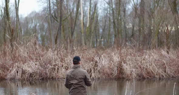 Man Fishing At Lakeshore In Forest