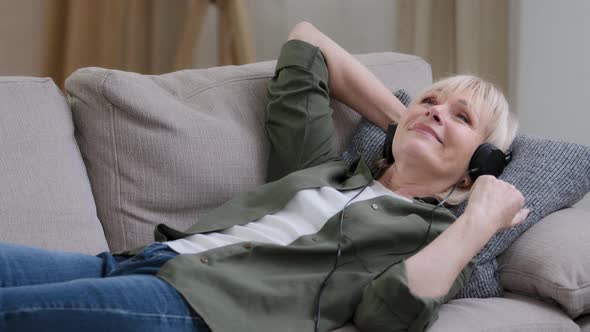 Relaxed Resting Old Caucasian Woman in Headphones Happy Carefree Grandmother Lying on Couch at Home