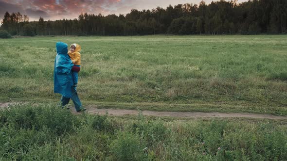 Woman Walks in the Park in the Evening with a Small Child