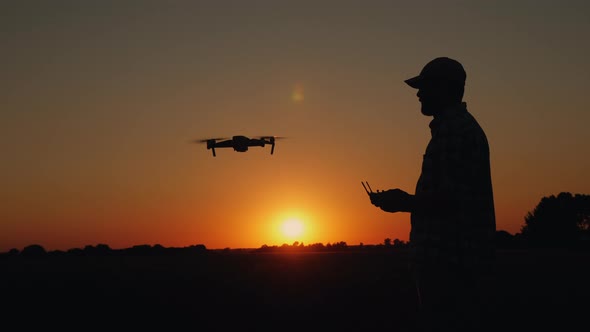 Silhouette of a Man at Sunset Takes Off a Drone