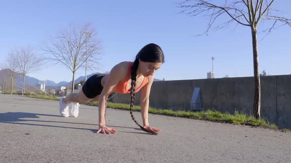 Young Woman doing pushups on pavement, Handheld Circle Pan Left