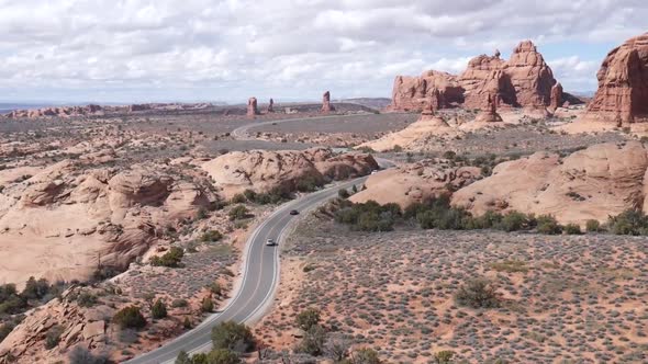 Cars driving down a long desert road.