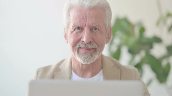Close Up of Old Man Smiling at Camera While Using Laptop in Office