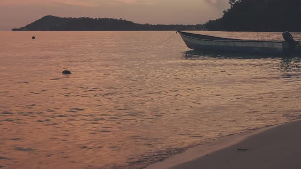 Local Wooden Boat Near the Beach During Sunset . Dusk at Gam Iisland. Calm Waves on the Ocean