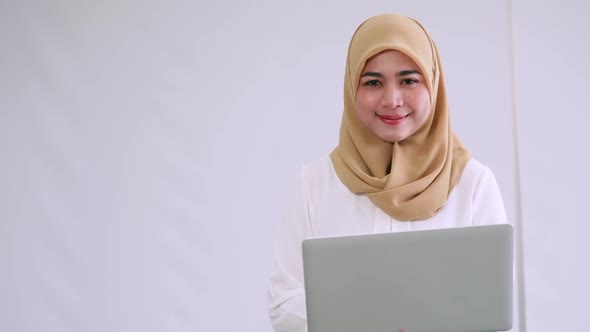 Portrait of young Asian Muslim business woman with laptop.