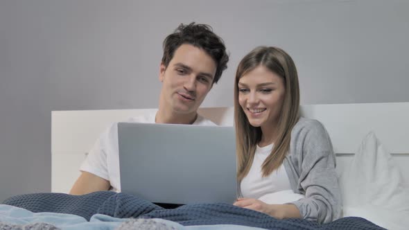 Online Video Chat By Happy Young Couple in Bed on Laptop