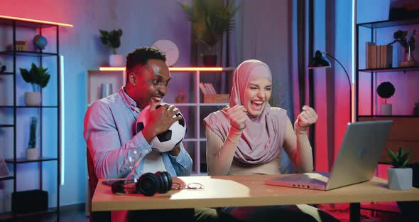 Male and Female Friends Remotely Supporting their Favourite Team on Laptop from home