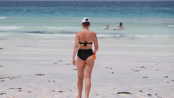 Young Woman in a Black Swimsuit Walks Into the Turquoise Ocean on Paradise Beach