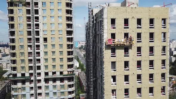 Insulation the Facade of Skyscraper Mineral Rock Wool. Workers Work in Suspended Cradle 