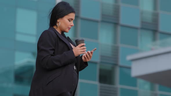 Young Successful Serious Hispanic Businesswoman Walks Down Street Against on Background Office