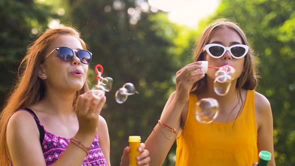 Teenage Girls Blowing Bubbles in Summer Park