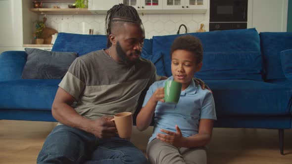 Positive African Father and Adorable Son Resting and Bonding in Domestic Room