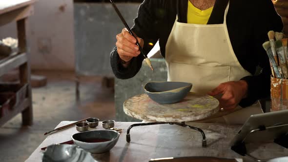 Attentive male potter painting on bowl