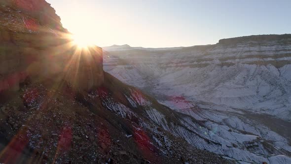 Flying over desert terrain covered in snow as the sun rises