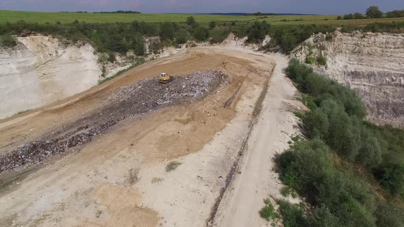 Digger moves garbage in junkyard. Aerial shot.