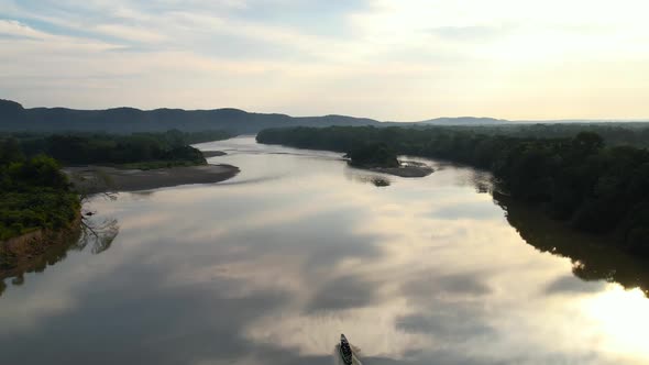 A small boat going up a tranquil river in the Amazon on a perfectly calm afternoon