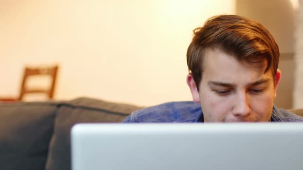 Man sitting on sofa and using laptop in living room