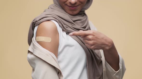 Unrecognizable Muslim Woman Demonstrating Shoulder with Medical Plaster After Vaccination and