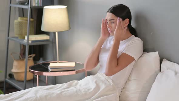 Young Latin Woman with Headache Sitting in Bed