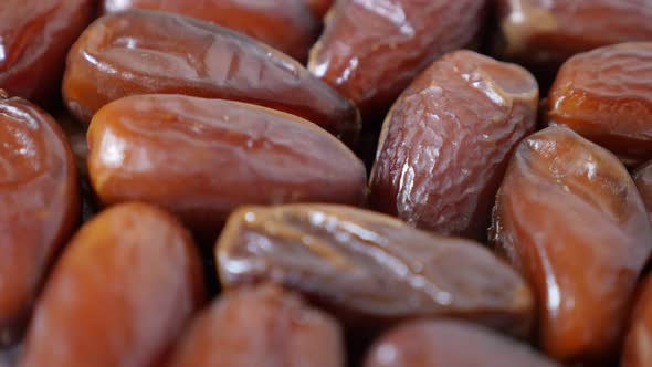 Tasty and exotic dates palm fruit on white reflective surface 4K 2160p 30fps UltraHD  tilting footag