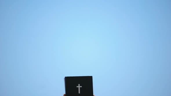 Man Reaching Out Hands to Sky Holding Bible, New Testament, Ten Commandments