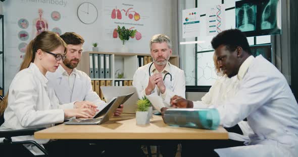 Male and Female Doctors Holding Consultation with Professional Bearded Main Doctor