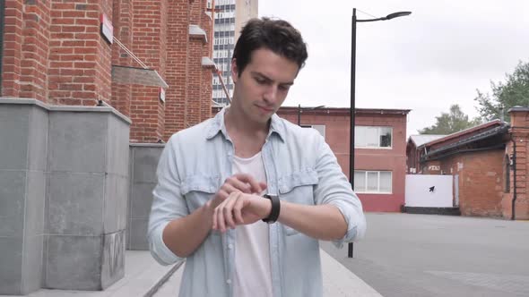 Man Walking on Street and Using Smartwatch