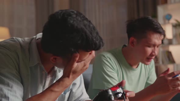 Young Asian Friends With Joystick Playing Video Games And Disappointed