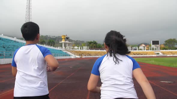 Back View Of Boy And Girl Running At Stadium