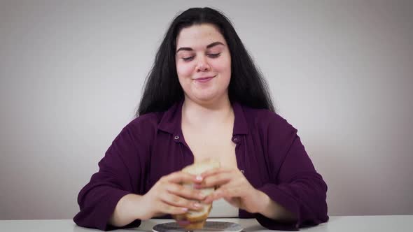 Positive Caucasian Obese Girl Eating Sandwich. Plump Woman with Overweight Problem Eating Unhealthy