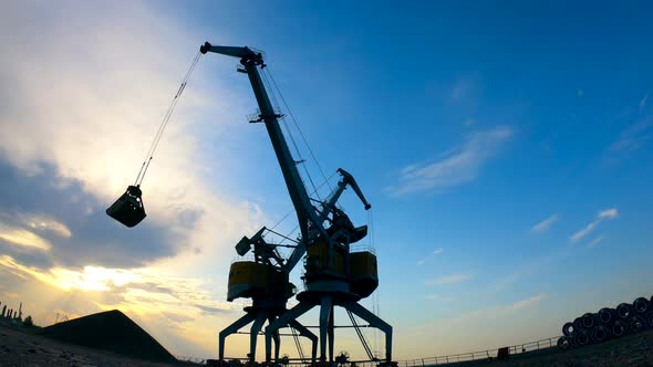 Sunset Site with Rubble Getting Relocated By the Industrial Cranes, Machines.